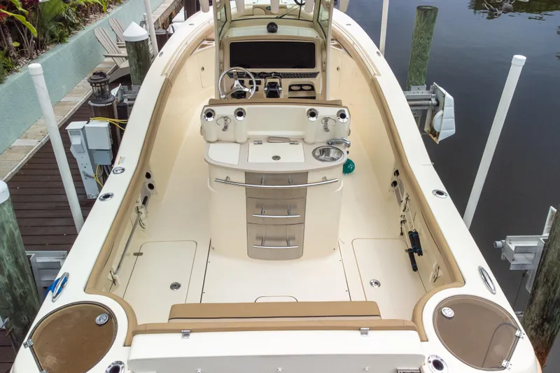 Slide: The Image of 2015 Scout 275 LXF boat interior with helm, storage, and seating at dock. - 27