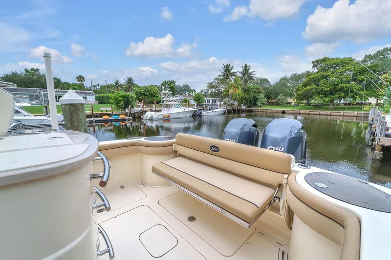 Slide: The Image of 2015 Scout 275 LXF boat docked in a scenic marina with lush greenery. - 30