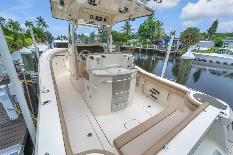 Slide: The Image of 2015 Scout 275 LXF boat interior at dock, featuring seating and helm station. - 40