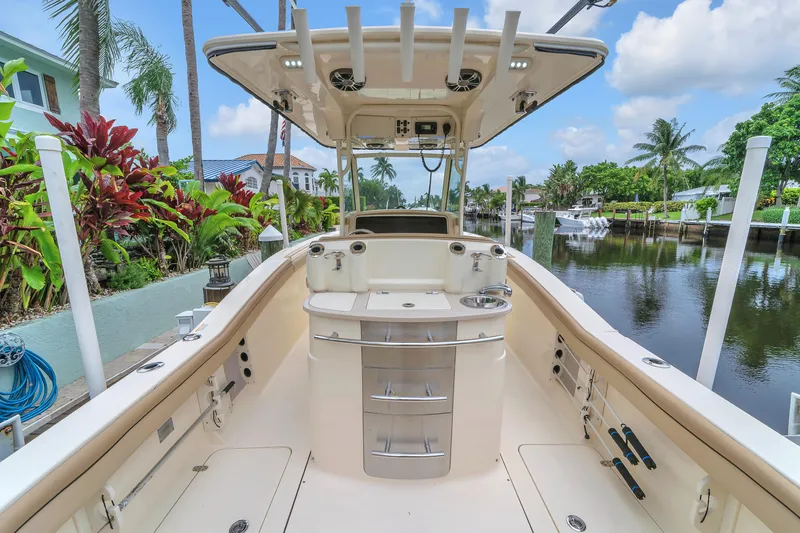 Slide: The Image of 2015 Scout 275 LXF boat interior with fishing amenities, docked by a tropical canal. - 42