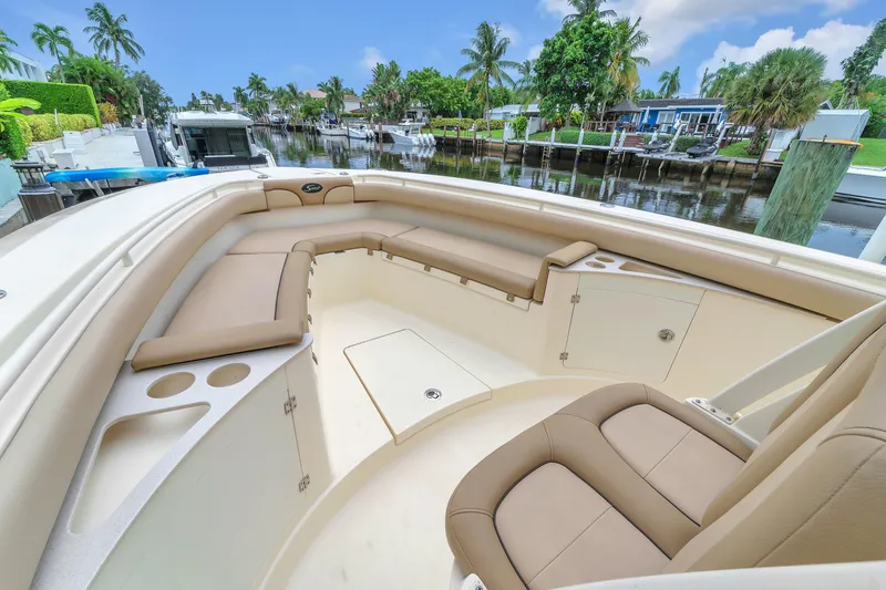 Slide: The Image of 2015 Scout 275 LXF boat interior with beige seating and cup holders, docked by a canal. - 44