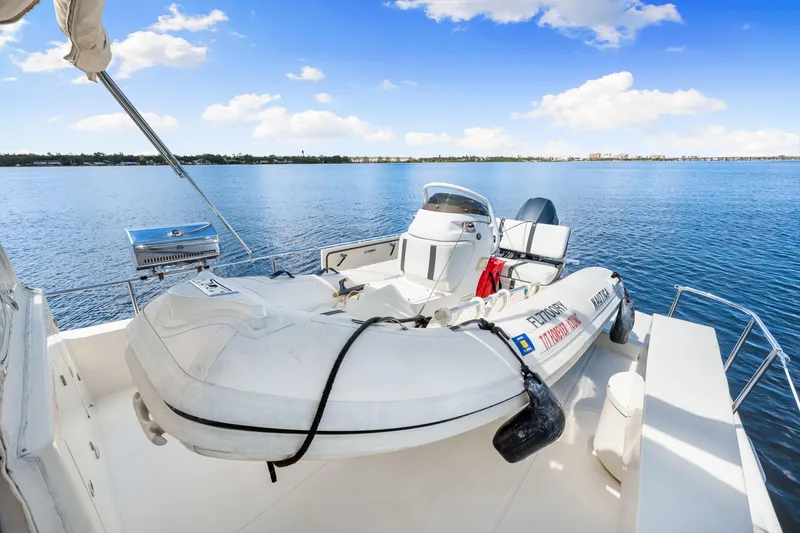 Slide: The Image of 2007 Hampton 558 Pilothouse yacht with inflatable boat on deck, overlooking serene blue waters. - 11