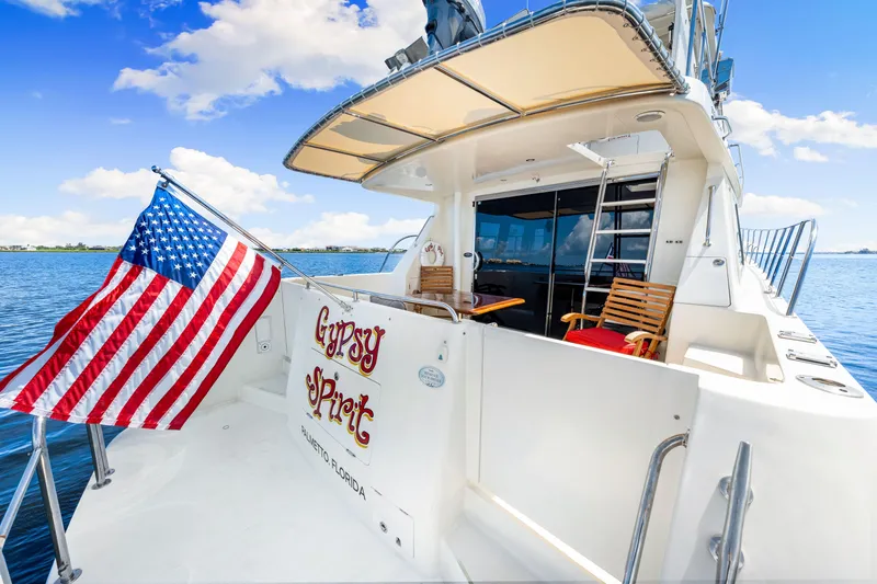 Slide: The Image of 2007 Hampton 558 Pilothouse yacht with American flag, named "Gypsy Spirit," docked in serene waters. - 51