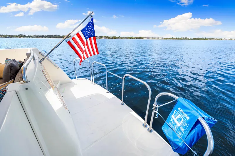 Slide: The Image of 2007 Hampton 558 Pilothouse yacht with American flag on calm water. - 52