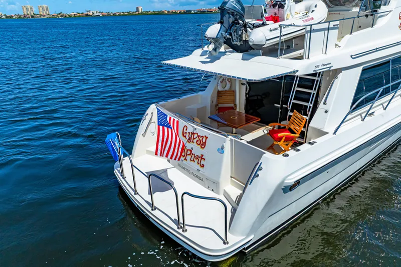 Slide: The Image of 2007 Hampton 558 Pilothouse yacht on water, featuring deck chairs and American flag. - 81
