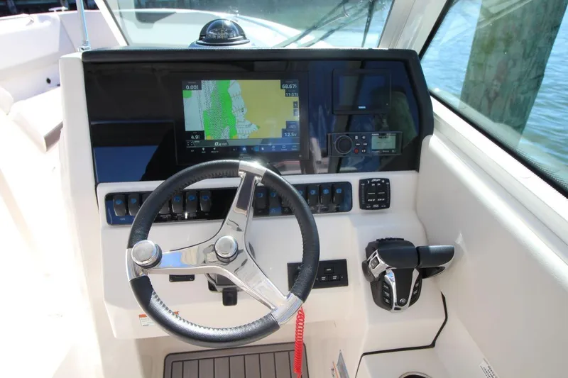 Slide: The Image of 2023 Sailfish 276 DC boat dashboard with steering wheel and navigation display. - 14