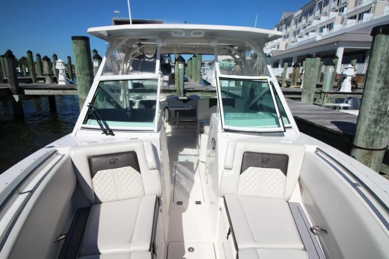 Slide: The Image of 2023 Sailfish 276 DC boat interior with cushioned seating at a marina dock. - 17