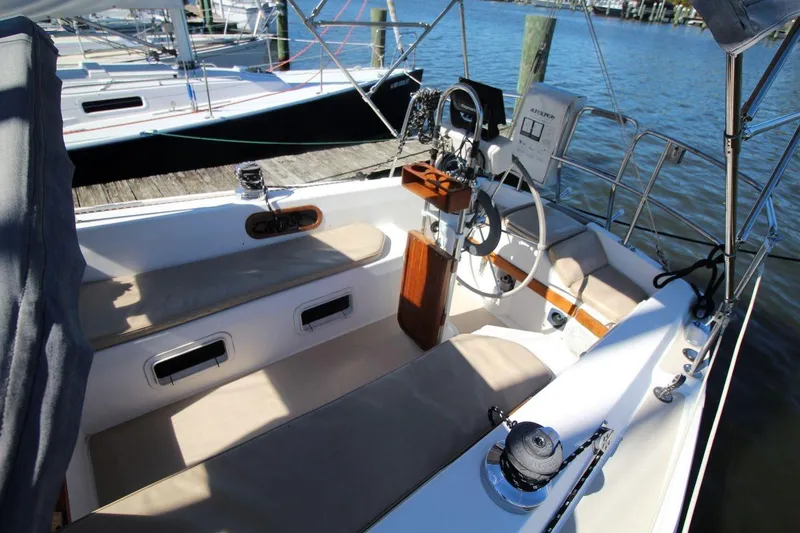 Slide: The Image of 1988 Catalina 34 sailboat cockpit with steering wheel and seating, docked by the water. - 12