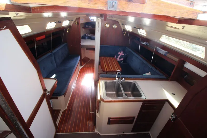 Slide: The Image of Interior of 1988 Catalina 34 sailboat with wood accents and blue seating. - 17