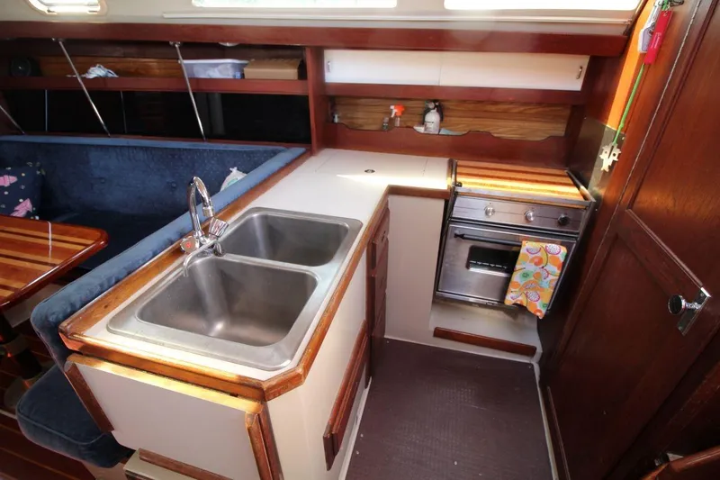 Slide: The Image of 1988 Catalina 34 yacht kitchen with dual sink, stove, and wooden cabinetry. - 18