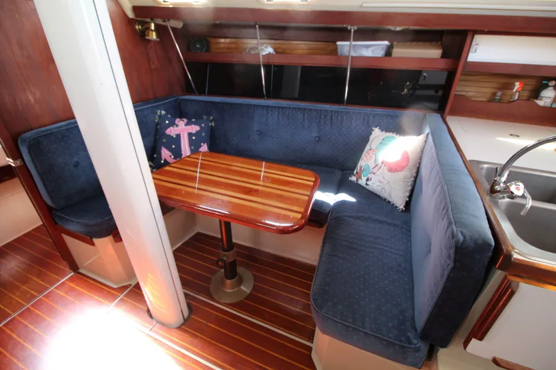 Slide: The Image of Interior of 1988 Catalina 34 sailboat with blue cushioned seating and wooden table. - 19