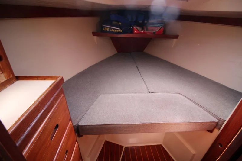 Slide: The Image of Cozy cabin interior of a 1988 Catalina 34 sailboat with cushioned berth and wooden storage. - 21