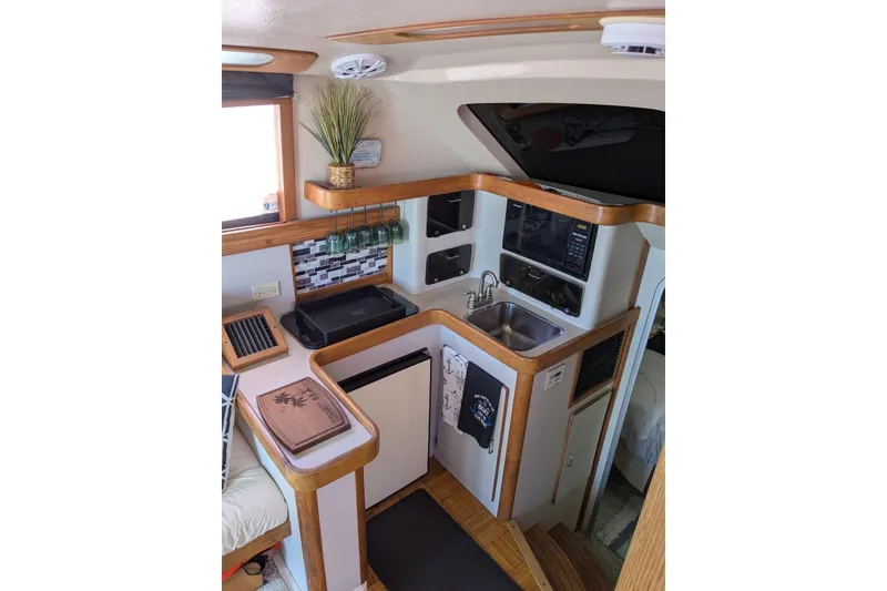 Slide: The Image of 1992 Luhrs Tournament 320 Convertible yacht interior kitchen with sink, fridge, and wooden accents. - 21
