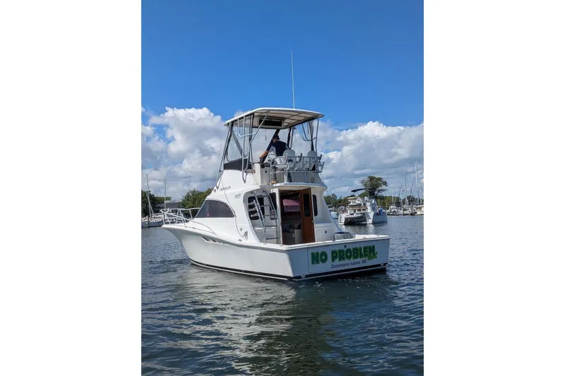 Slide: The Image of 1992 Luhrs Tournament 320 Convertible boat on water, clear sky, marina background. - 3