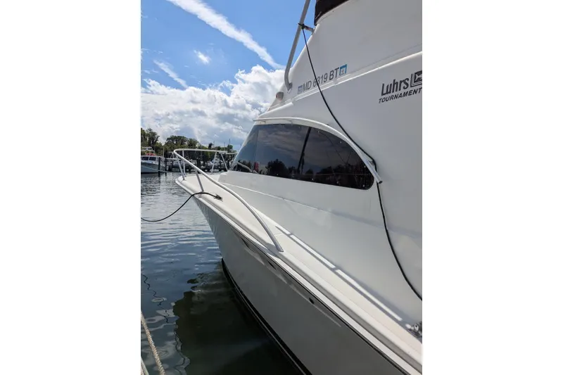 Slide: The Image of 1992 Luhrs Tournament 320 Convertible boat docked on calm water under a blue sky. - 5