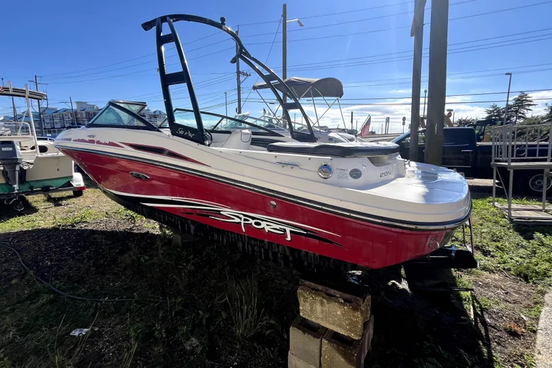 Slide: The Image of 2012 Sea Ray 205 Sport boat with red and white design, parked outdoors. - 2