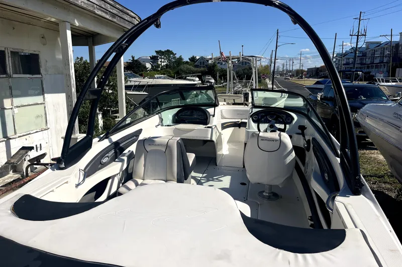 Slide: The Image of 2012 Sea Ray 205 Sport boat interior with seating and steering wheel, parked outdoors. - 4