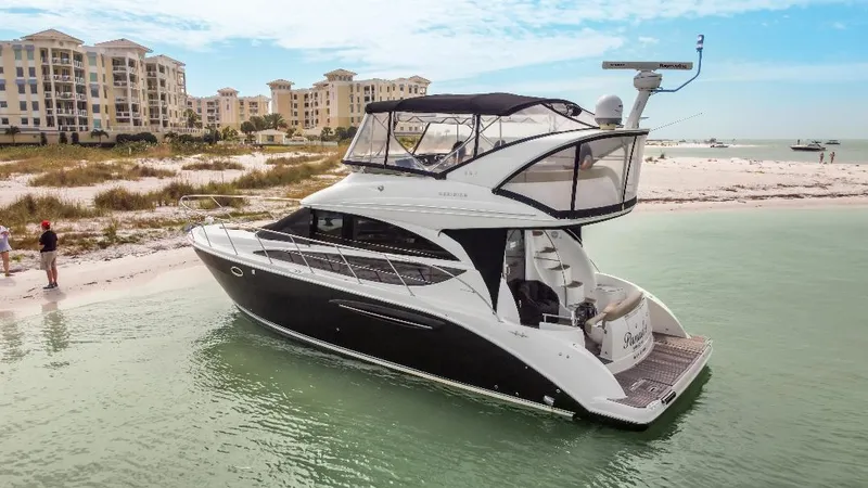 Slide: The Image of 2016 Meridian 391 Sedan yacht near sandy beach and luxury buildings. - 2