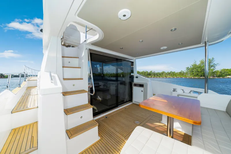 Slide: The Image of Luxurious 2018 Azimut 50 Fly yacht deck with seating, table, and stairs, overlooking serene waters. - 14