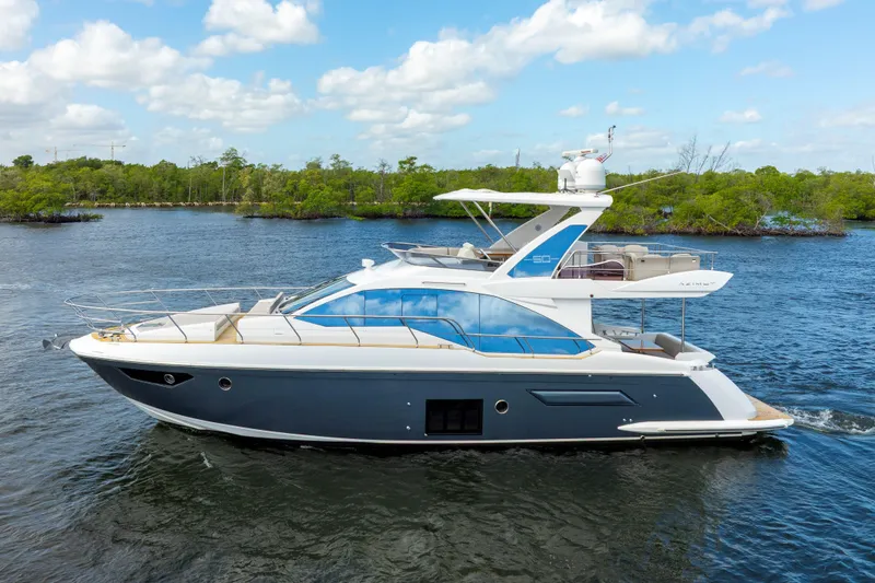 Slide: The Image of 2018 Azimut 50 Fly yacht cruising on a scenic waterway under a blue sky. - 6