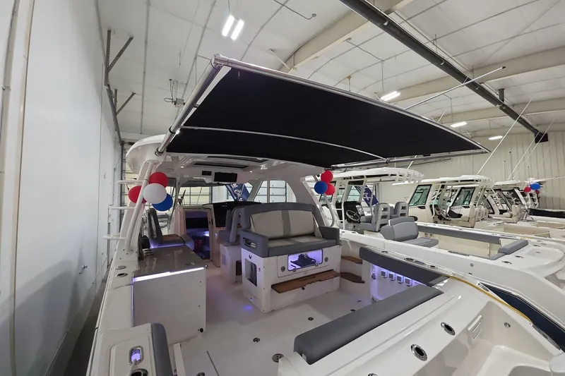 Slide: The Image of 2026 Boston Whaler 380 Realm boat interior with seating and canopy in showroom. - 30
