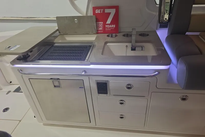 Slide: The Image of 2026 Boston Whaler 380 Realm boat kitchen with grill, sink, and storage drawers. - 33