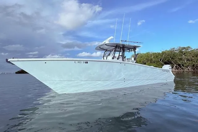 Slide: The Image of 2019 Freeman 34 boat on calm water, clear sky, and lush greenery in the background. - 28