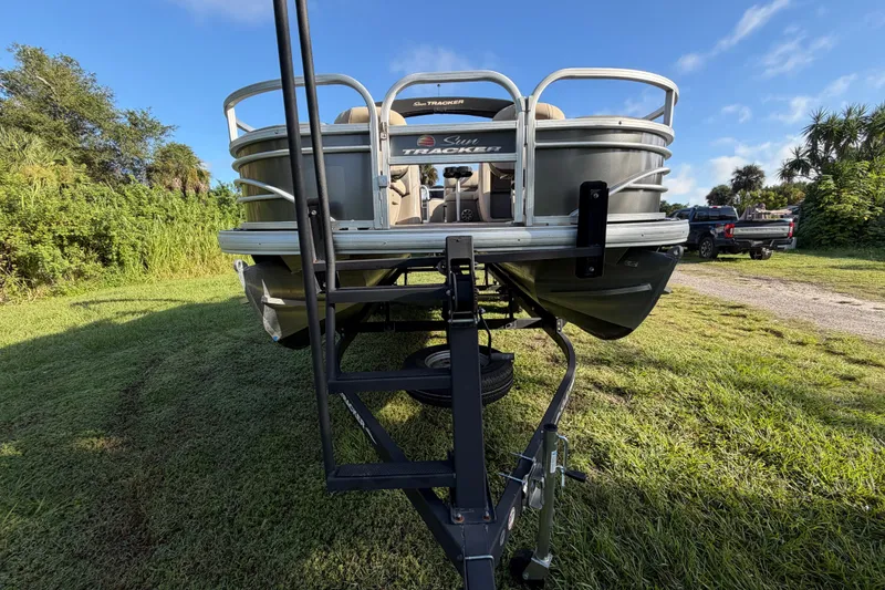 Slide: The Image of 2023 Sun Tracker Fishin' Barge 20 DLX on trailer, parked on grassy area. - 33