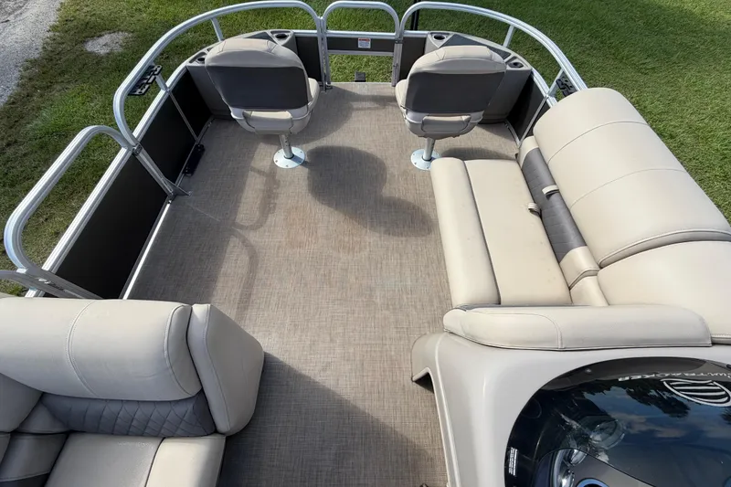 Slide: The Image of 2023 Sun Tracker Fishin' Barge 20 DLX interior with seating and helm, on grassy background. - 36