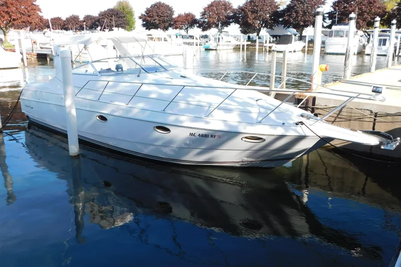 The Image of 1996 Chris-Craft 340 Crowne boat docked in a marina, reflecting on calm water. - 0
