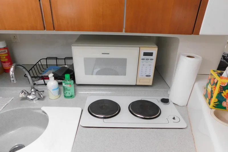 Slide: The Image of Compact kitchen area with microwave, stove, and sink on a Chris-Craft 340 Crowne boat. - 77