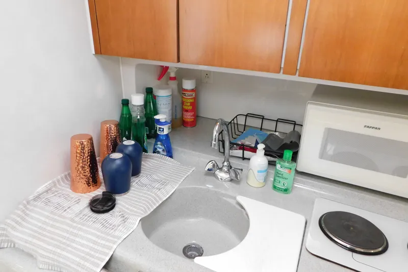 Slide: The Image of Kitchen area in 1996 Chris-Craft 340 Crowne boat with sink, microwave, and cleaning supplies. - 78