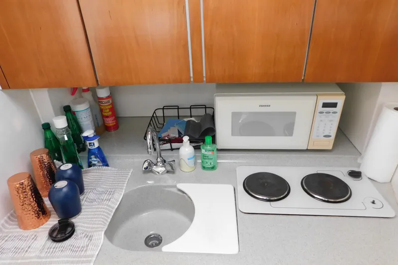 Slide: The Image of Compact kitchen area in a 1996 Chris-Craft 340 Crowne boat with microwave and sink. - 79