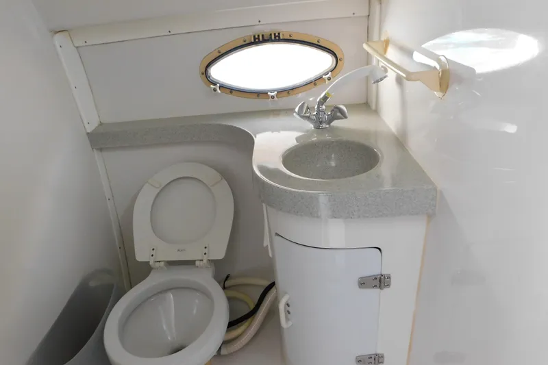 Slide: The Image of 1996 Chris-Craft 340 Crowne boat bathroom with toilet, sink, and porthole window. - 86