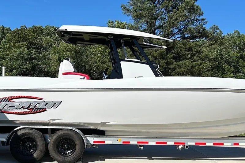 Slide: The Image of 2023 Sunsation 32 CCX boat on trailer, sleek design, white exterior, forest background. - 2