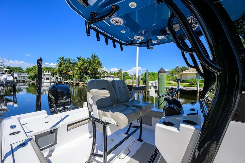 Slide: The Image of 2023 Sportsman Masters 247OE Bay Boat interior with seating and console, docked by palm trees. - 19