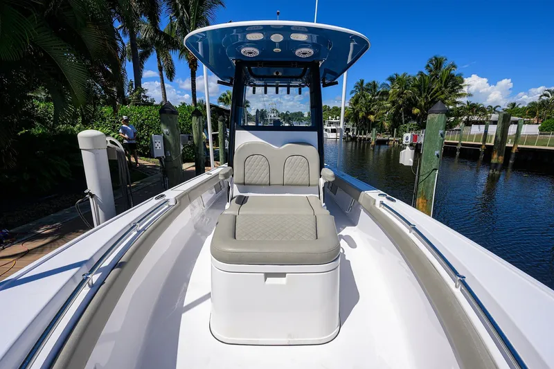 Slide: The Image of 2023 Sportsman Masters 247OE Bay Boat docked by palm trees and waterway. - 28