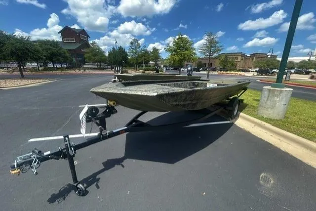 Slide: The Image of 2026 Tracker Grizzly 1754 Utility boat on trailer in parking lot under blue sky. - 2