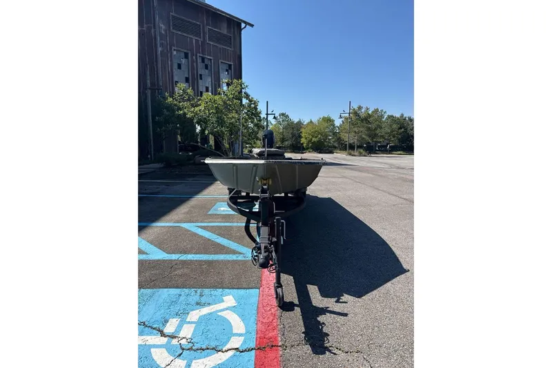 Slide: The Image of 2026 Tracker Grizzly 1654 T Sportsman boat parked in a lot near a building. - 3