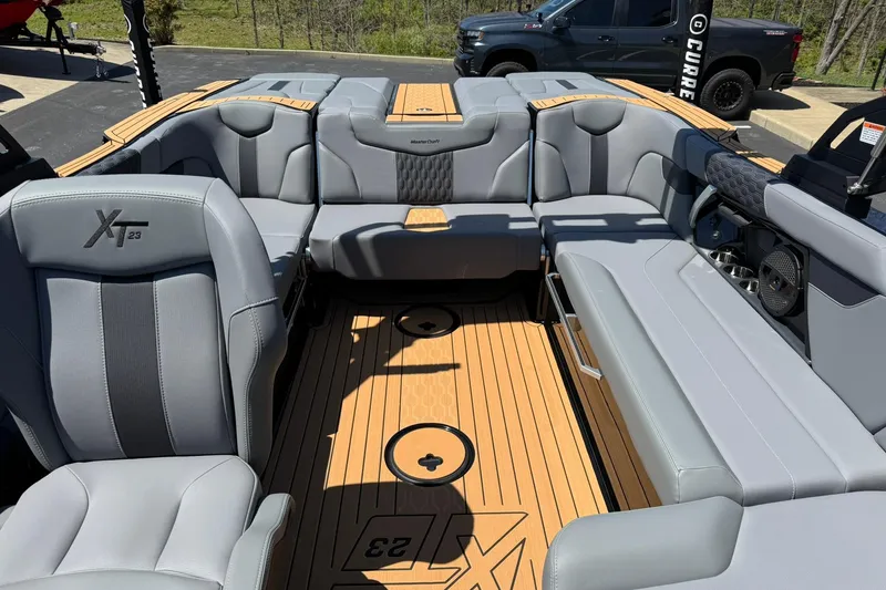 Slide: The Image of 2025 MasterCraft XT23 boat interior with gray seating and teak flooring. - 11