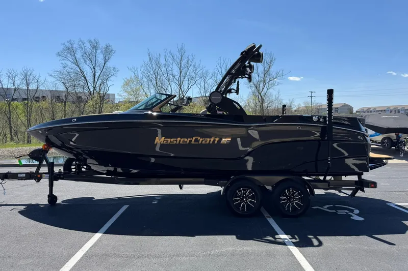 Slide: The Image of 2025 MasterCraft XT23 boat in a parking lot, sleek black design, on a trailer. - 6
