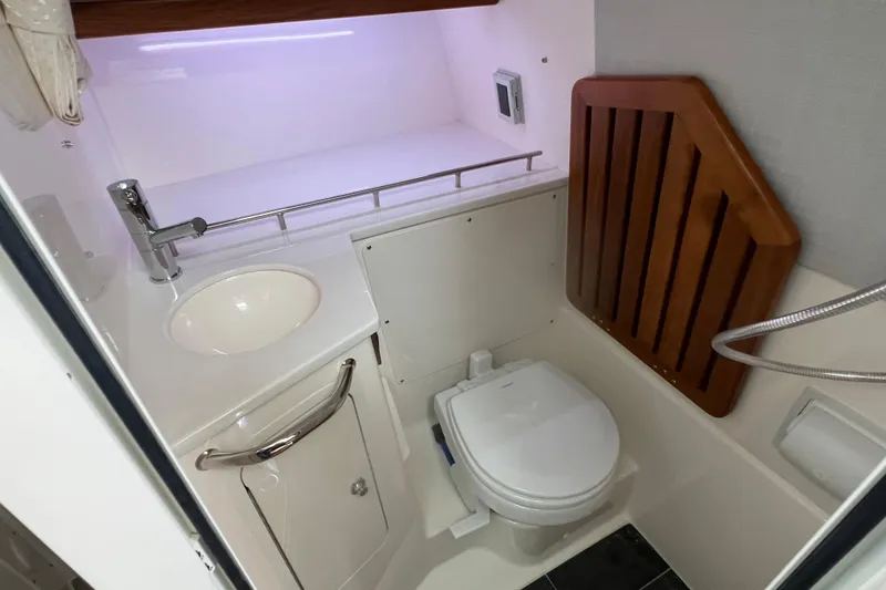 Slide: The Image of 2026 Boston Whaler 350 Realm boat bathroom with sink, toilet, and wooden accents. - 17