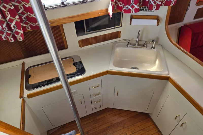 Slide: The Image of 1989 Pearson 37-2 yacht kitchen with sink, stove, and microwave, featuring wood accents. - 24