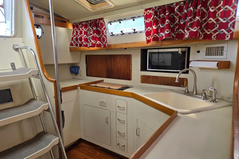 Slide: The Image of 1989 Pearson 37-2 yacht interior kitchen with red curtains and modern amenities. - 25