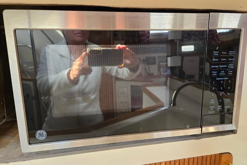 Slide: The Image of GE microwave in a 1989 Pearson 37-2 yacht kitchen, reflecting a person taking a photo. - 29