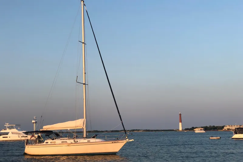 Slide: The Image of Sailboat Pearson 37-2 (1989) on calm water near a lighthouse at sunset. - 40