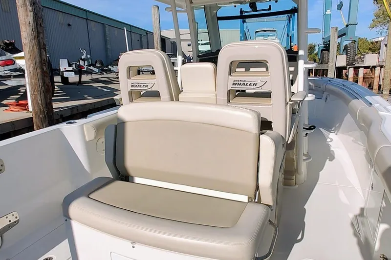 Slide: The Image of 2019 Boston Whaler 330 Outrage boat interior with beige seating and helm station. - 12