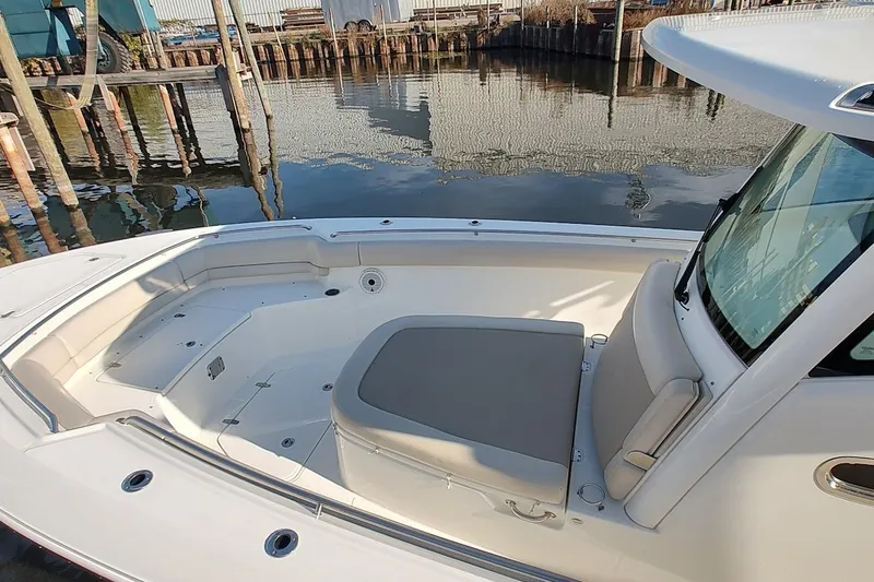 Slide: The Image of 2019 Boston Whaler 330 Outrage boat interior with seating, docked by calm water. - 13