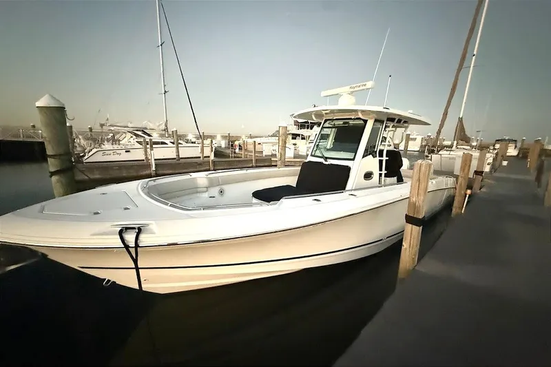 Slide: The Image of 2019 Boston Whaler 330 Outrage docked at marina, showcasing sleek design and spacious deck. - 20