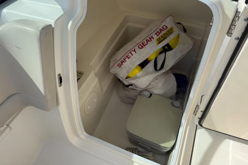 Slide: The Image of Storage compartment in 2015 Boston Whaler 230 Vantage with safety gear bag and portable toilet. - 12
